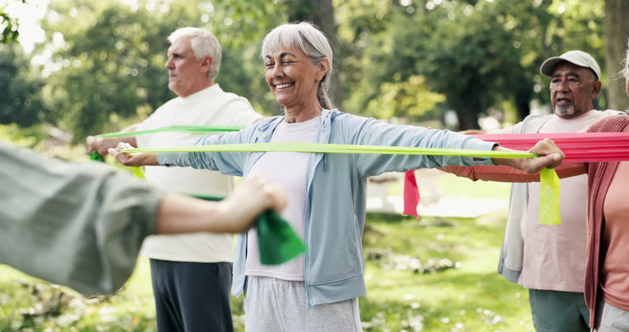 Resistance band, fitness and class with old woman in nature for workout, stretching and health. Exercise, retirement and wellness with senior people learning in park for personal trainer and club