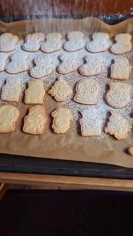 Christmas cookies sprinkled with powdered sugar. Close-up, cooking process. Festive homemade pastries.