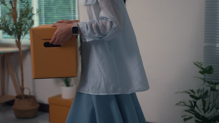 Young Asian woman feeling tired after carrying boxes, resting on the sofa in her new apartment. Relocation and moving day concept