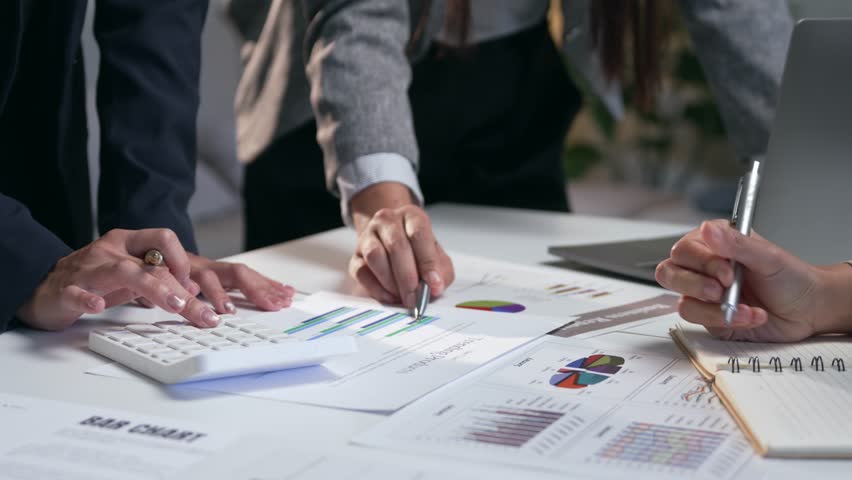 Professional team of analysts collaborating on a business project, reviewing financial reports with charts and graphs in the office