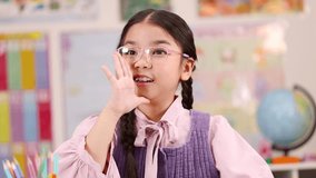 Elementary girl with pink glasses whispers secret at desk in colorful classroom, soft lighting - Powered by Shutterstock - Get 15% off with code: PIKWIZARD15