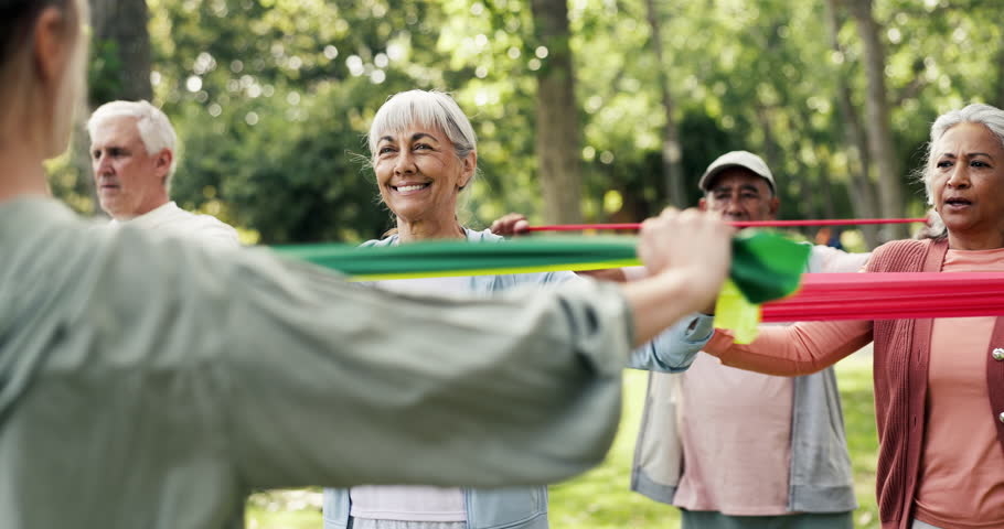 Elderly group, coach and resistance band with exercise in nature for workout class or training. Senior people, fitness or stretching with personal trainer for flexibility, health or wellness in park