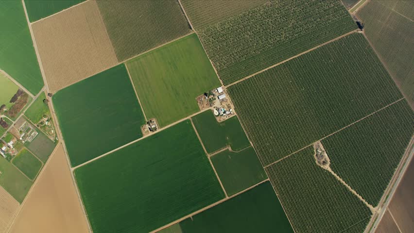 A detailed 4K aerial view of extensive agricultural fields in a patchwork pattern, likely showing different crops in a fertile region like the San Joaquin Valley.