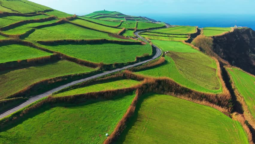 Aerial view of the unique scenic landscape of Sao Miguel Island with a country road through bright green fields, Azores, Portugal.