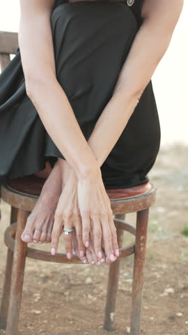 Woman, alone, pensive woman sitting on a chair hugging knees outdoors at sunset. Vertical video