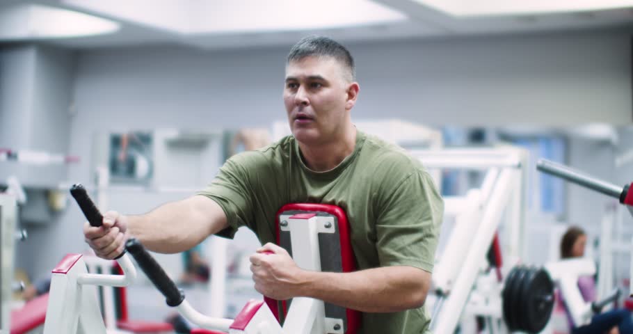 Middle aged Caucasian man working out in the gym. A focused Caucasian man works his back muscles intensely using the hammer machine, maintaining strong form throughout his gym session.