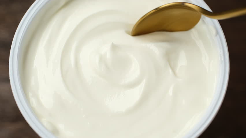 Sour cream or greek yogurt scoop with spoon, close up
