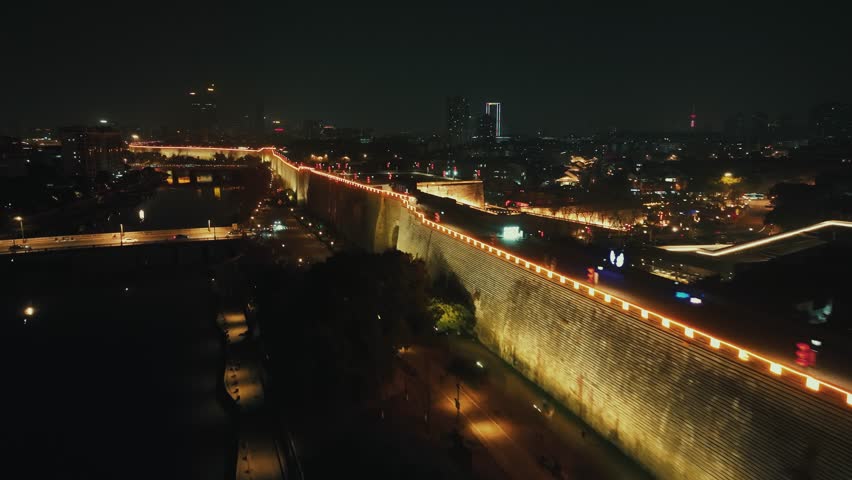 Nanjing, China. A nighttime cityscape with a large concrete wall illuminated by streetlights.