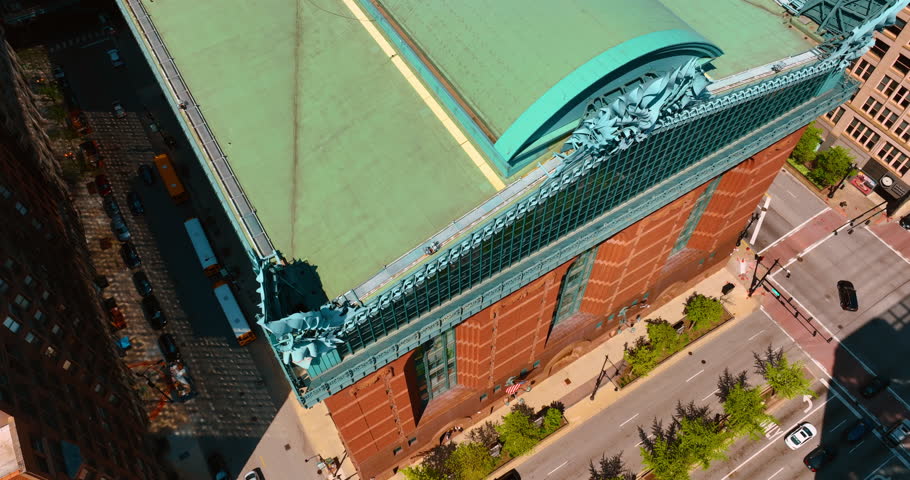 Rising over the green roof of Harold Washington Library. Many cars go by the roads near the building. Top view. Chicago, Illinois, USA.