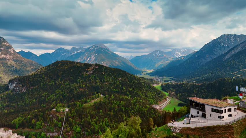 Evergreen pine tree woods covering the beautiful mountains. Dramatic cloudscape hanging over the tops of the spectacular rocks. Tyrol, Austria.