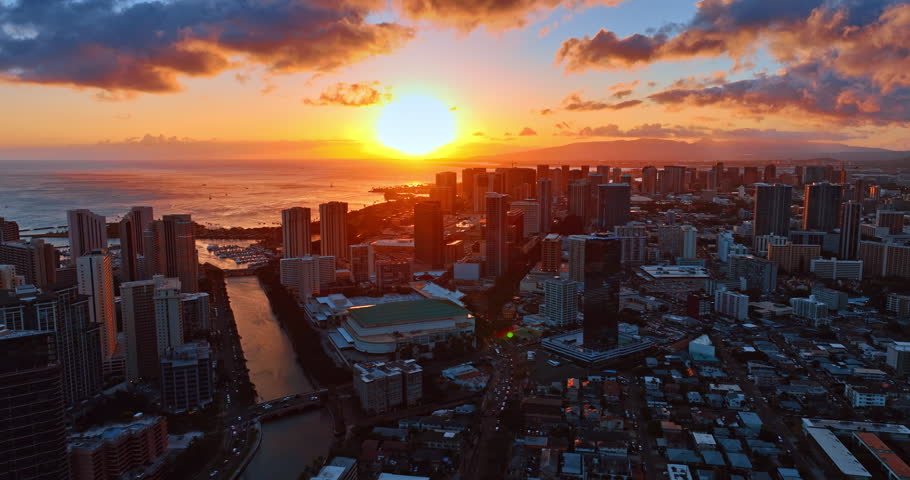 Fantastic sunset above the Pacific Ocean. Drone flight over the cityscape of Honolulu, Hawaii, USA at dusk.