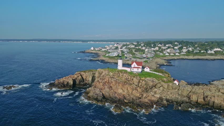 A drone view captures a dynamic flythrough of Nubble Lighthouse and its adjacent building at York Beach, offering a unique perspective of the iconic landmark 4k