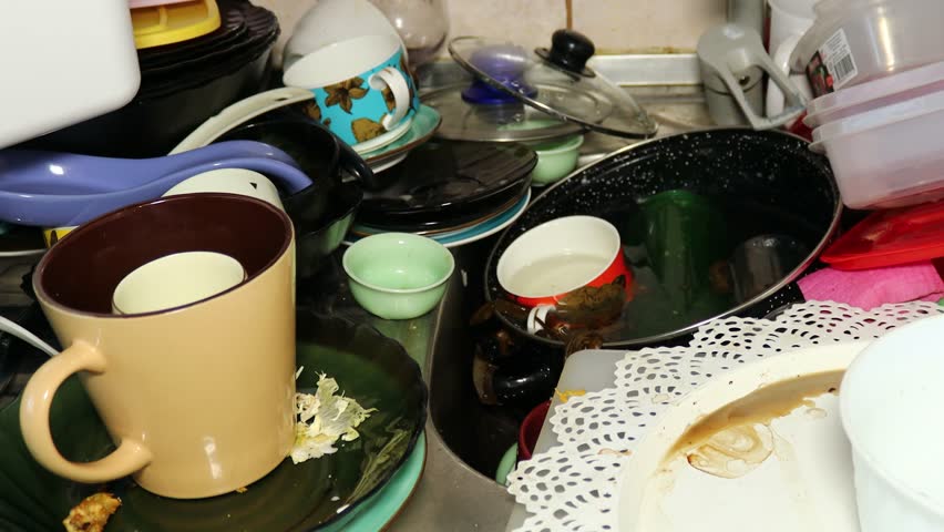 A cluttered kitchen countertop with dirty dishes and cups.