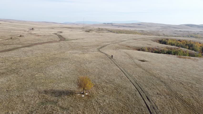 Man riding a cross motorcycle on a mountain plateau, drone view. Off-road motorcycle rider on mountain plain. Cross bike rider. Mountainous terrain destroyed by all-terrain vehicles and ATVs.