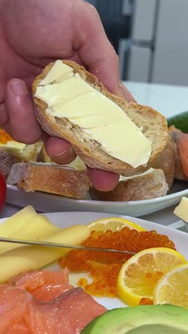 bread with butter and red caviar. red caviar being spooned onto a buttered slice of bread on a wooden board, with an open tin of caviar visible, ready for a gourmet snack or appetizer. Fine dining 