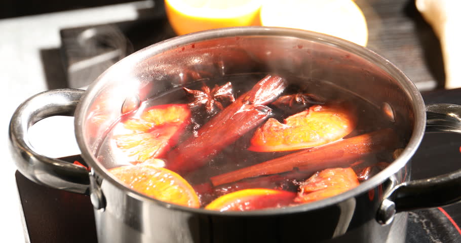 Taking hot mulled wine from pot with ladle at stove, closeup