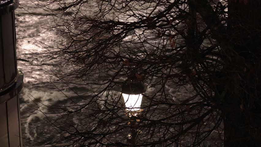 Stockholm, Sweden Water rushes at night below a bridge and a street lamp in the Norrstrom River in the downtown. 
