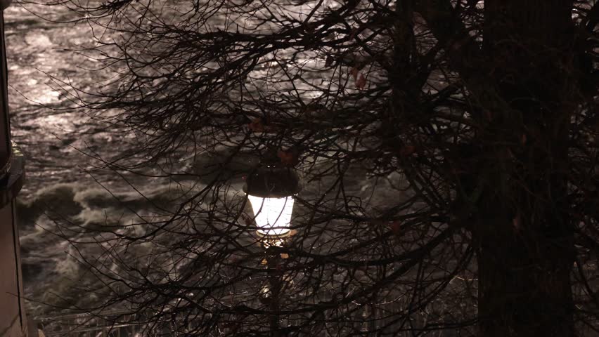 Stockholm, Sweden Water rushes at night below a bridge and a street lamp in the Norrstrom River in the downtown. 