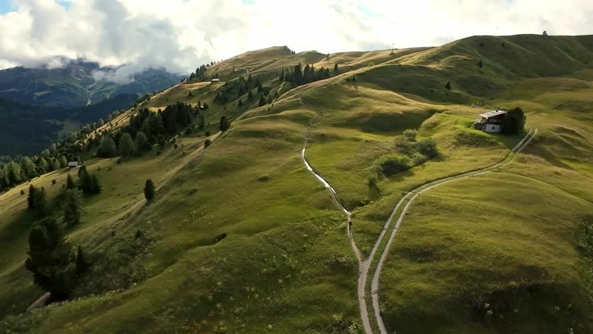 Peaceful mountain scene with clouds, Tranquil terrain featuring jagged hills and floating clouds, Idyllic landscape exhibiting rough hills beneath sky filled with wandering clouds
