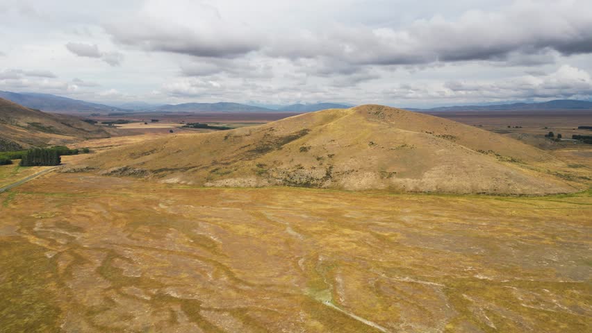 Aerial drone forward moving shot over countryside highway leading through golden meadows in Central Otago, New Zealand
