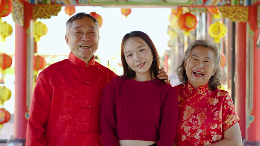 Portrait of asian father, mother, and their teenage daughter share laughter and happiness while talking at a vibrant Chinese temple adorned with lanterns, capturing a perfect family moment.