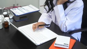 Asian female doctor using laptop for teleconsultation and checking patient's EHR record, wearing glasses,demonstrating modern healthcare,online medical services  professional expertise in hospital - Powered by Shutterstock - Get 15% off with code: PIKWIZARD15