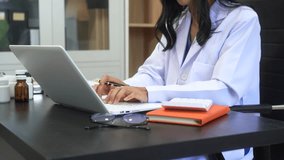 Asian female doctor using laptop for teleconsultation and checking patient's EHR record, wearing glasses,demonstrating modern healthcare,online medical services  professional expertise in hospital - Powered by Shutterstock - Get 15% off with code: PIKWIZARD15