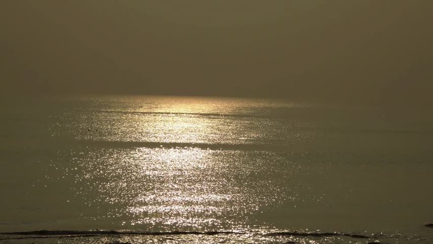 Moody coastal beach landscape under overcast sky with calm sea waves