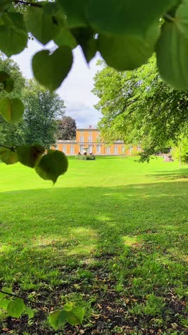 stockholm green meadow with trees and distant yellow building on sunny day