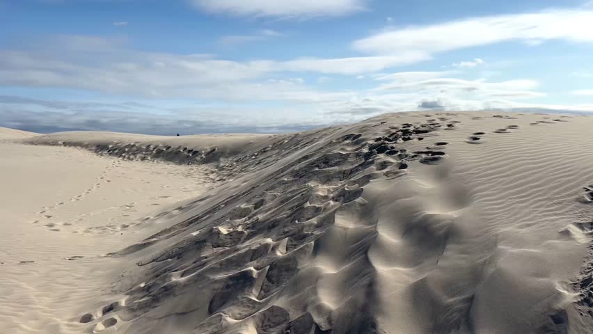 Boy Runs and Jumps Off Sand Dune for a Thrilling Fall. Kid runs up to the edge and leaps off the steep dune slope. Motion, speed, and fun family travel concepts.