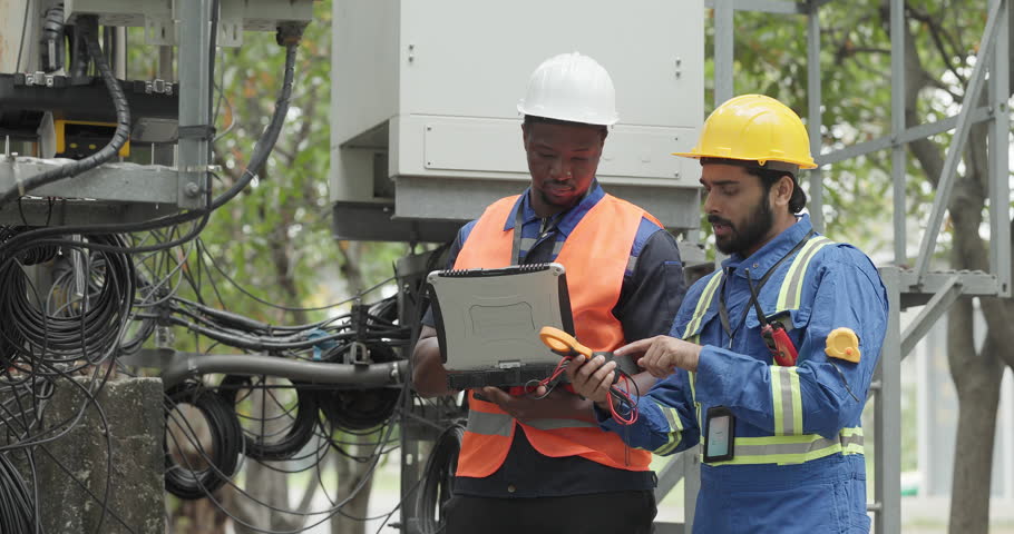 Telecom engineer and technician inspect communication equipment during network maintenance and upgrade operation. Infrastructure inspection, troubleshooting, cable management for reliable connectivity