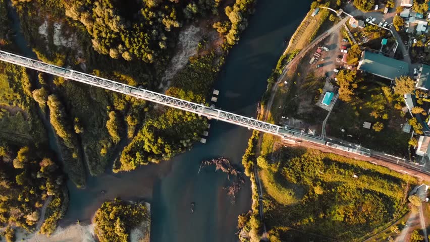 Aerial view of a bridge crossing a river surrounded by green forest.