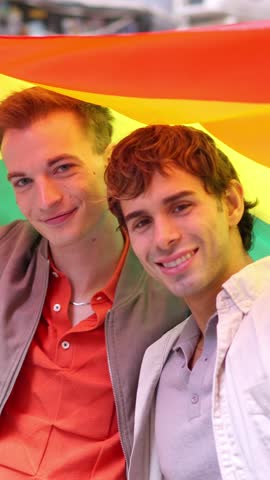 Happy gay couple smiling with pride rainbow flag