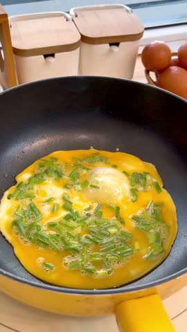 Frying eggs in a pan, flipping omelet while cooking on a stove.