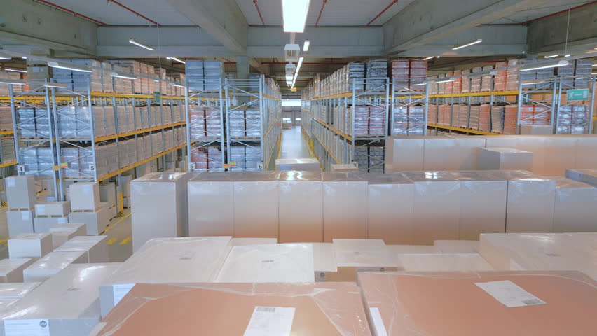 A vast warehouse reveals rows of neatly stacked crates and boxes, highlighting efficient storage and distribution logistics. The perspective emphasizes the organized layout and spaciousness.
