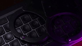 Handcuffs resting on a dark keyboard illuminated by blue light, symbolizing crime, justice, and law enforcement in a digital age with a focus on security and technology - Powered by Shutterstock - Get 15% off with code: PIKWIZARD15