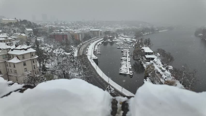 Prague, Czech Republic - December 03, 2023 - Podoli -  timelapse of panoramic view of a city harbor during a gentle snowfall with boats docked and snow-covered trees