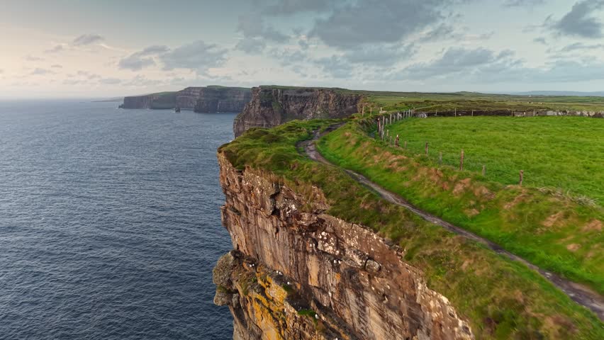 Aerial breathtaking cliffs of Moher in Ireland, County Clare. Flying over path near the edge of Cliff of Moher - one of the most popular tourist destinations in Ireland