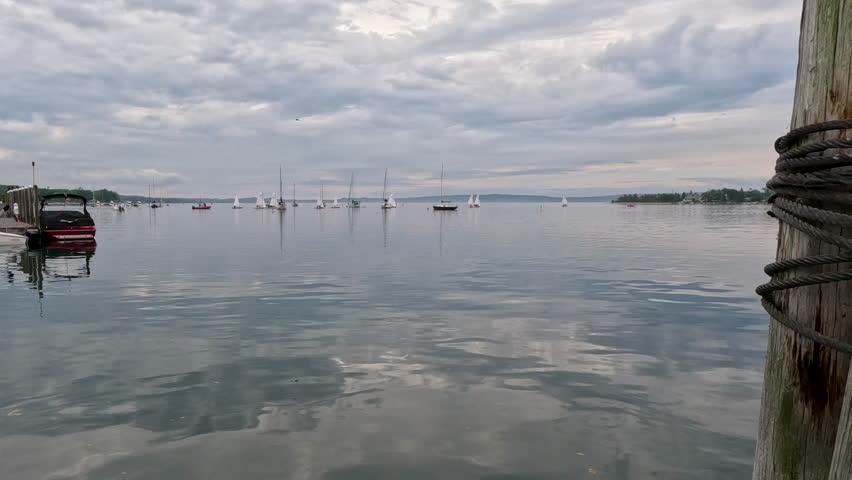 Boats Sailing in the Bay on Lake Michigan. Nautical scene with sailing boats on the water. A wooden bollard is in the foreground of view. On Lake Michigan in Northern Michigan, USA. Little Traverse Bay.