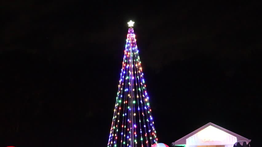 This outdoor Christmas decoration features a cone-shaped LED tree formed around a central pole. Strands of multicolored lights stretch downward evenly, creating a balanced geometric look. Florida