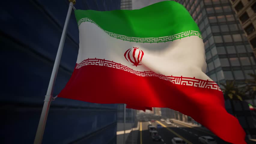 The national flag of Iran waves clearly along a modern city street during bright daylight, standing out against a structured and contemporary urban environment. Natural sunlight enhances the green, white, and red horizontal stripes while keeping the central emblem clearly visible, reinforcing strong national symbolism and cultural identity. The surrounding cityscape features organized streets, modern buildings, and light traffic, reflecting everyday urban life within a Middle Eastern and West Asian setting.

The composition avoids highlighting specific landmarks, allowing the scene to represent Iran in a broad and adaptable manner. Gentle movement of the flag adds realism and visual rhythm, while daylight conditions emphasize clarity, balance, and neutrality. The urban environment appears calm, functional, and orderly, supporting a professional and informative visual tone.

This scene effectively conveys themes of national identity, civic presence, and modern city life. It is well suited for international news coverage, regional analysis, travel-related storytelling, or background visuals that require a neutral and unbiased representation of Iran.
