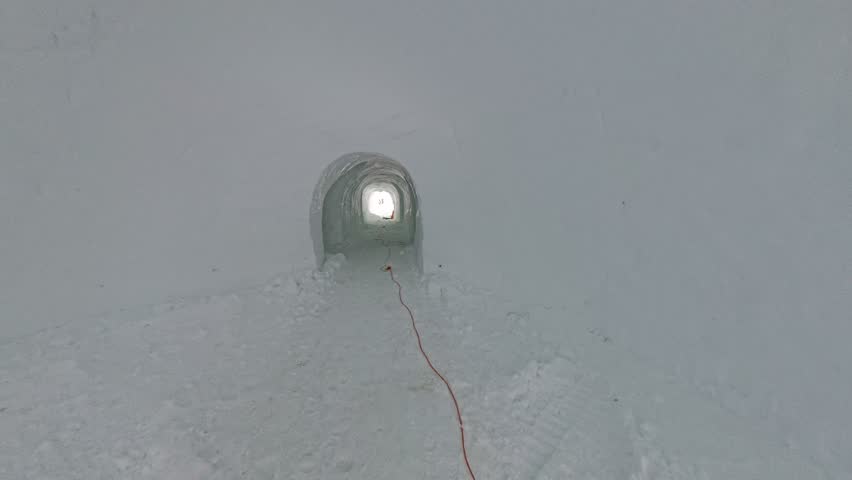 Walking through an ice igloo at Engstligenalp, Switzerland, showcasing frozen walls, icy textures and a unique alpine winter experience in a pristine mountain landscape.