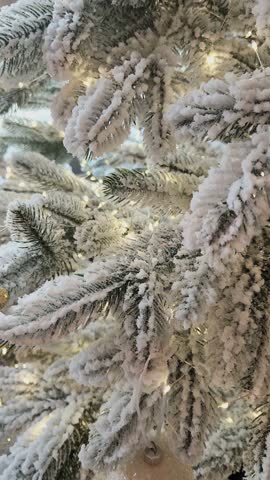 A Christmas tree with a white and gold Christmas tree ornament and garland. Close-up.