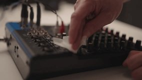 Close-up cropped shot of hand cleaning audio mixing console with soft cloth, removing dust from knobs and faders to ensure proper functionality and prolong life of sound production equipment. - Powered by Shutterstock - Get 15% off with code: PIKWIZARD15