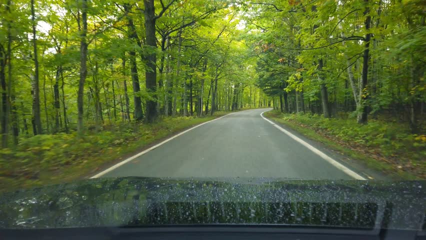 Driving through Scenic road- tunnel of trees in Michigan up north country side during early autumn time.
