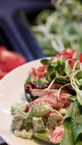 Close-up rotating shot of fresh mixed salad plate at bright self-serve buffet bar