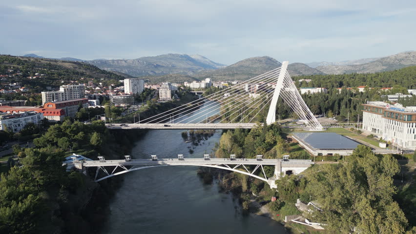 Cinematic aerial footage showcases the river Moraca flowing through the city of Podgorica, the capital and most populous city in Montenegro. Flying backwards.