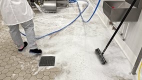 A Worker Rinses a Soapy Industrial Floor Using a Hose and Cleaning Tools - Handheld Shot - Powered by Shutterstock - Get 15% off with code: PIKWIZARD15