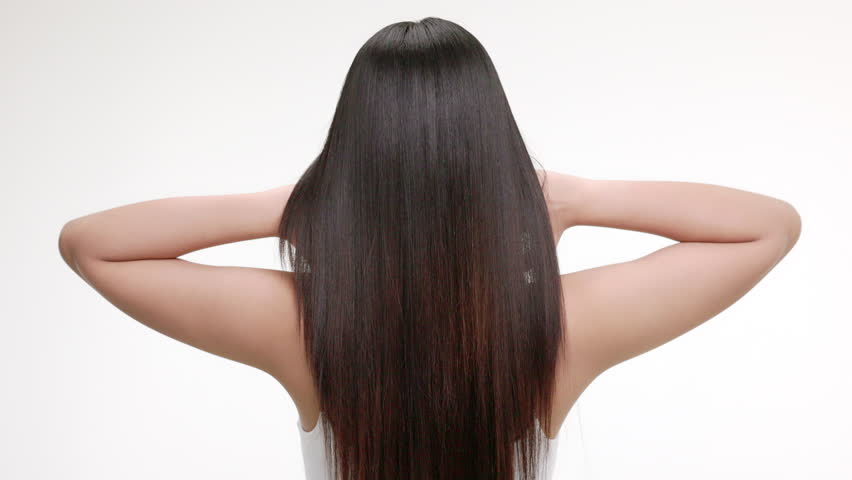 Slow motion rear view of young Asian girl shakes long straight hair. Female model is fluttering hair.