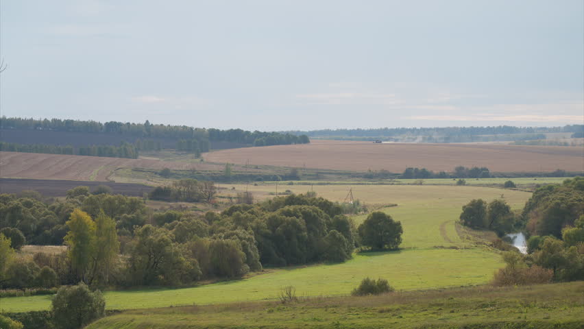 A beautiful scenic rural landscape featuring lush green fields, rolling hills, and trees